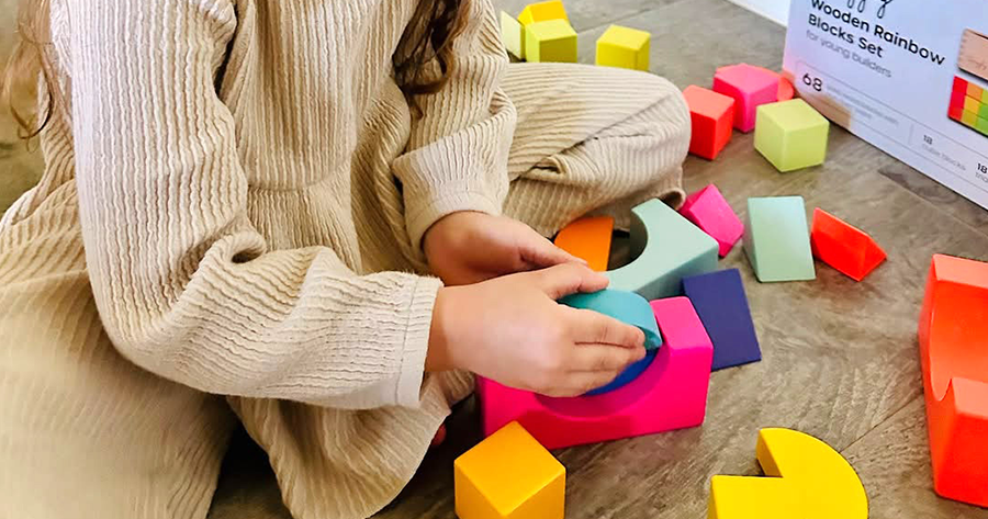 Child making imaginative structures using Quiggly’s colorful wooden block set