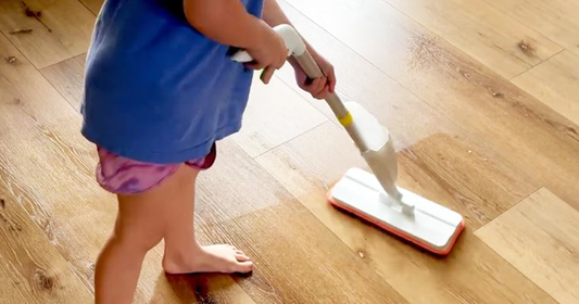 A kid using Quiggly's toy spray mop to clean the floor