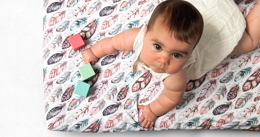 Quiggly travel cribs sheets sized for Guava Lotus travel crib and a baby doing tummy time with blocks