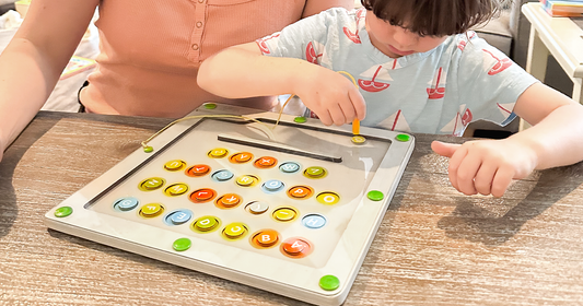 Young boy using a magnetic wand to move alphabet pieces on Quiggly’s wooden alphabet & color maze board