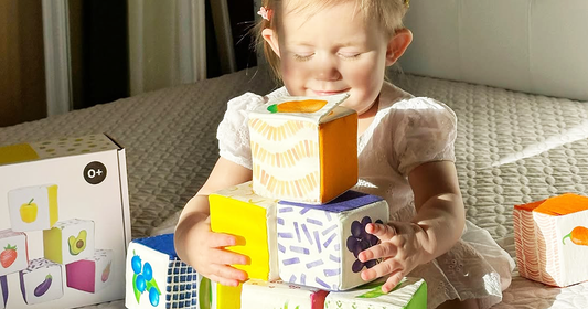 Smiling toddler embracing Quiggly’s soft and safe 100% cotton fabric blocks set