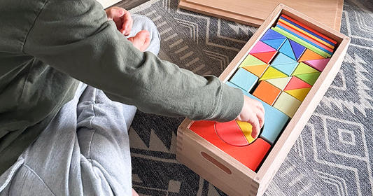 Child reaching for a wooden rainbow block from an organized Montessori-style storage box from Quiggly