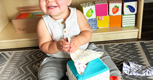 Cheerful baby grabbing beautifully designed soft fabric tissues from Quiggly’s tissue box toy
