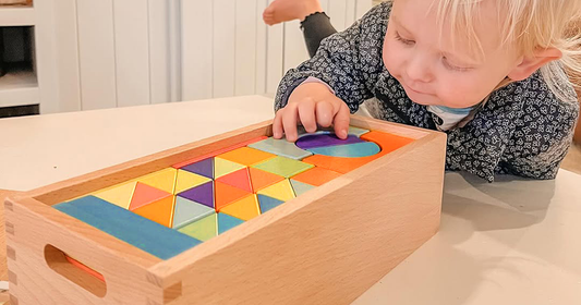 Curious child inspecting the visible wood grain of a rainbow block from Quiggly’s organized wooden set