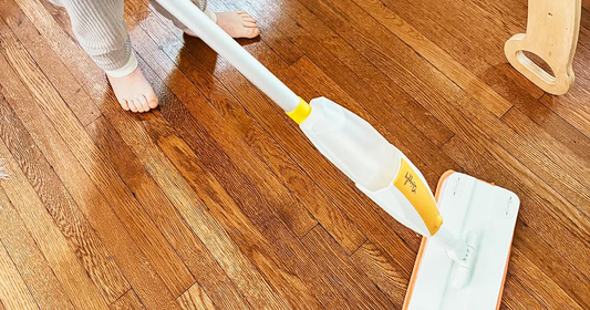 A child using Quiggly’s tiny real spray mop in a playroom