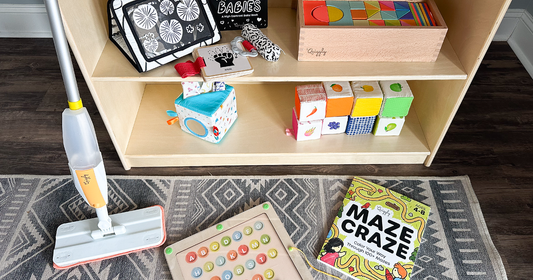 Quiggly's Montessori toys in a play area - including the kid spray mop, the black & white set, the colorful wooden blocks, the fabric tissue box toy, the soft blocks set, magnetic maze & maze craze book
