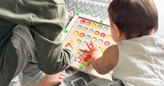 A kid & baby duo playfully solving the magnetic alphabet & color maze from Quiggly