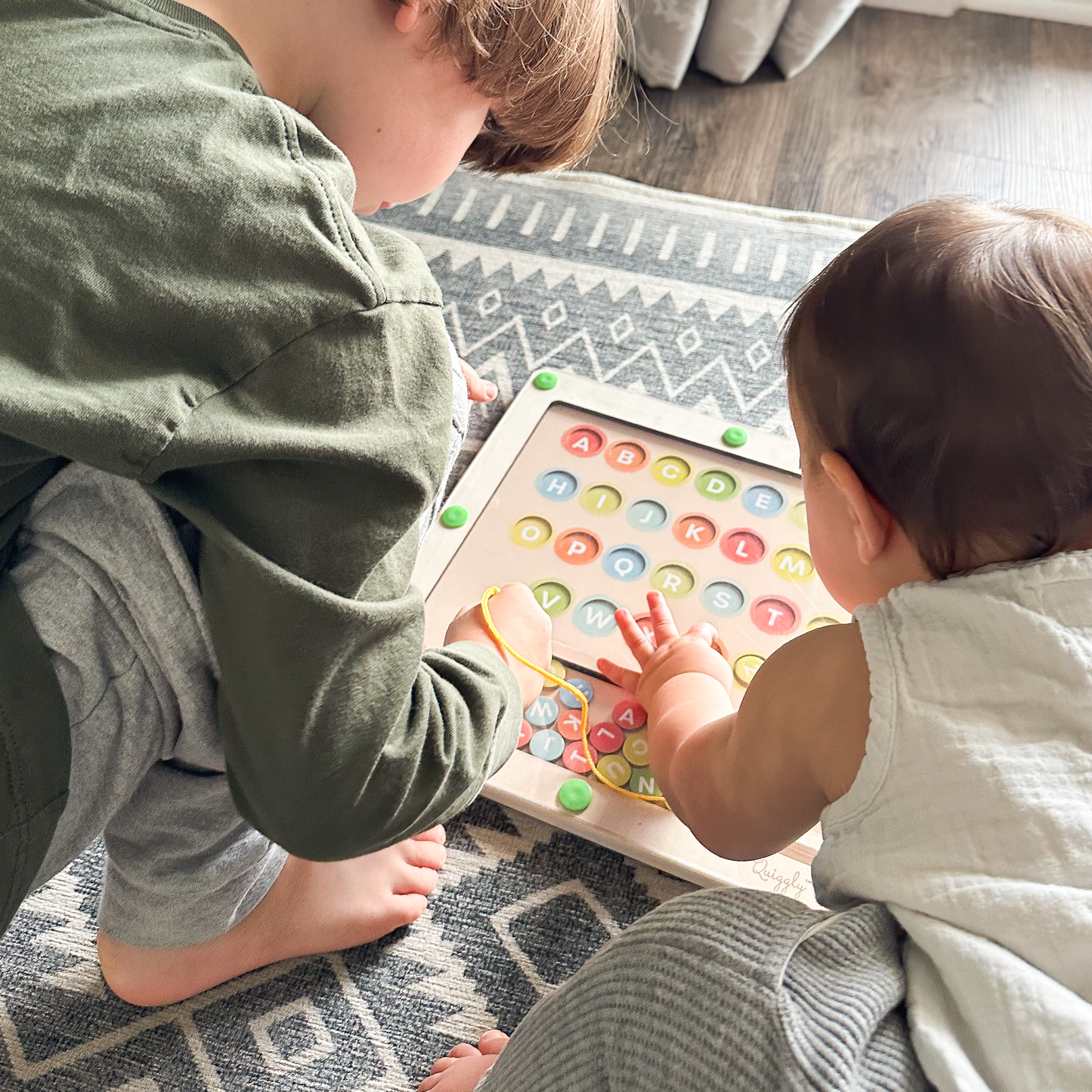 Siblings working together to solve magnetic maze board, promoting collaborative play