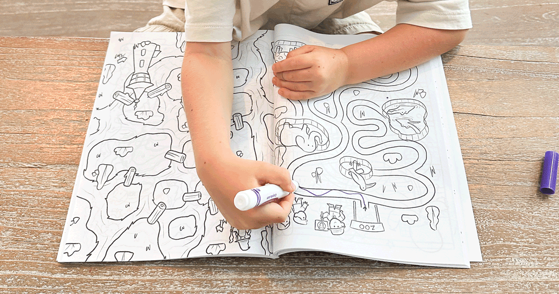 A kid solving a page in a maze book made for 4-8 years old