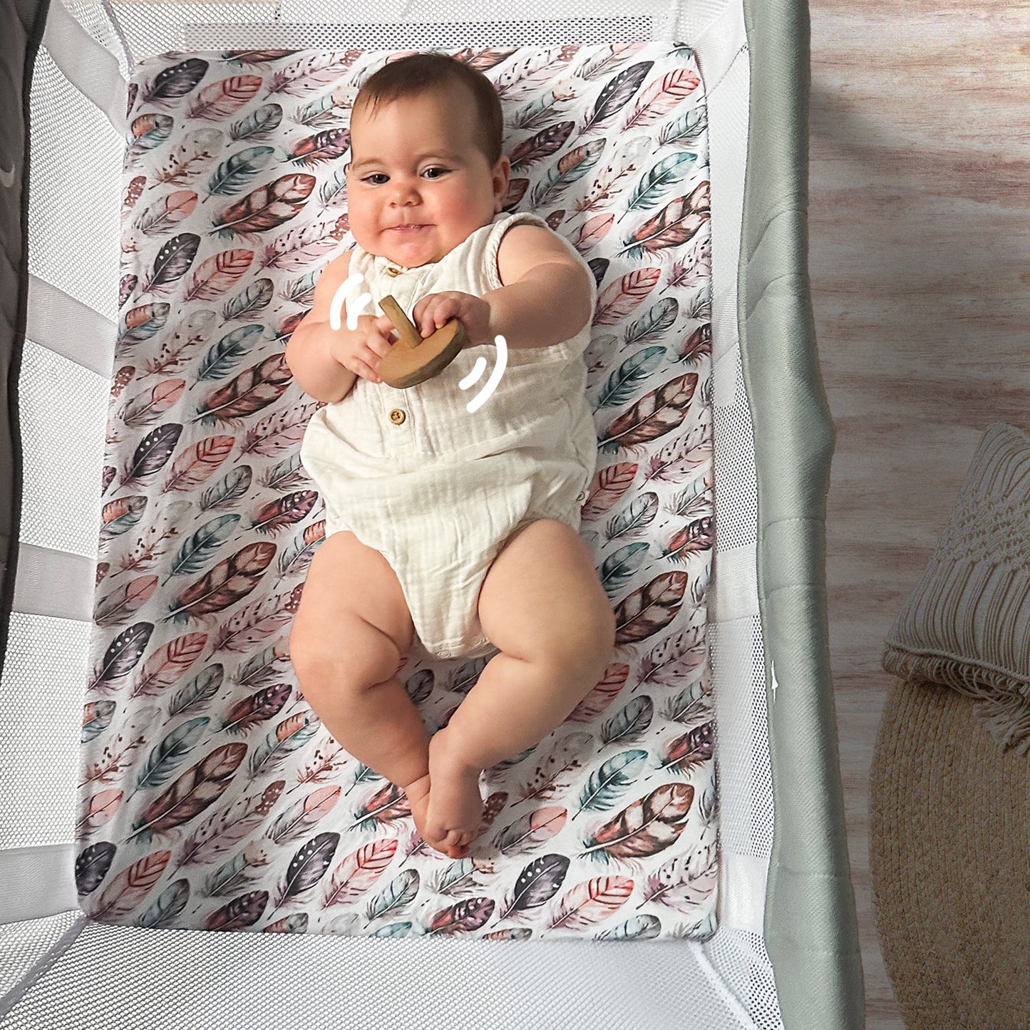 Baby playing comfortably inside Guava Lotus bassinet crib on Quiggly’s soft organic cotton sheet