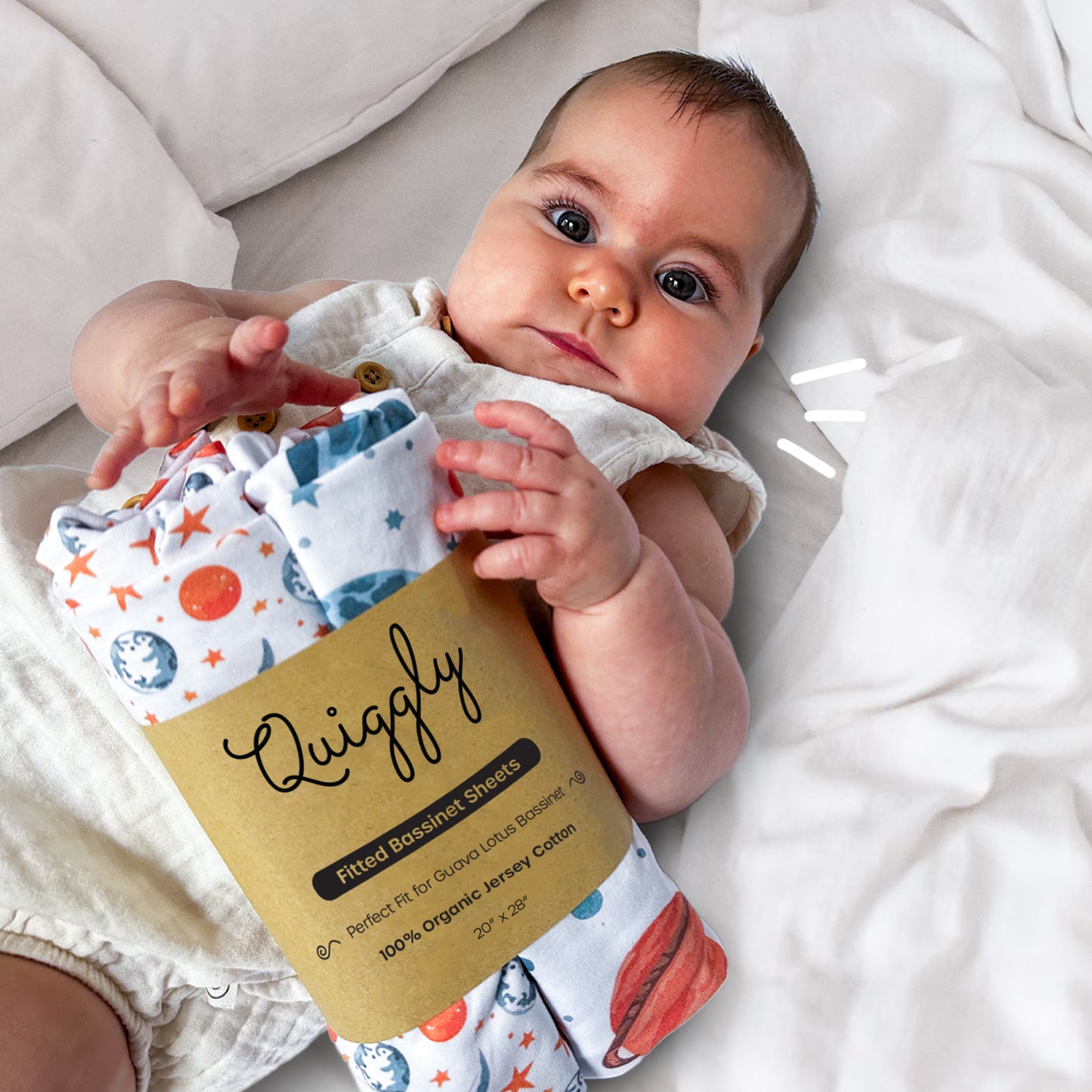 Baby holding a 2-packed bassinet crib sheet in Starry Slumber theme