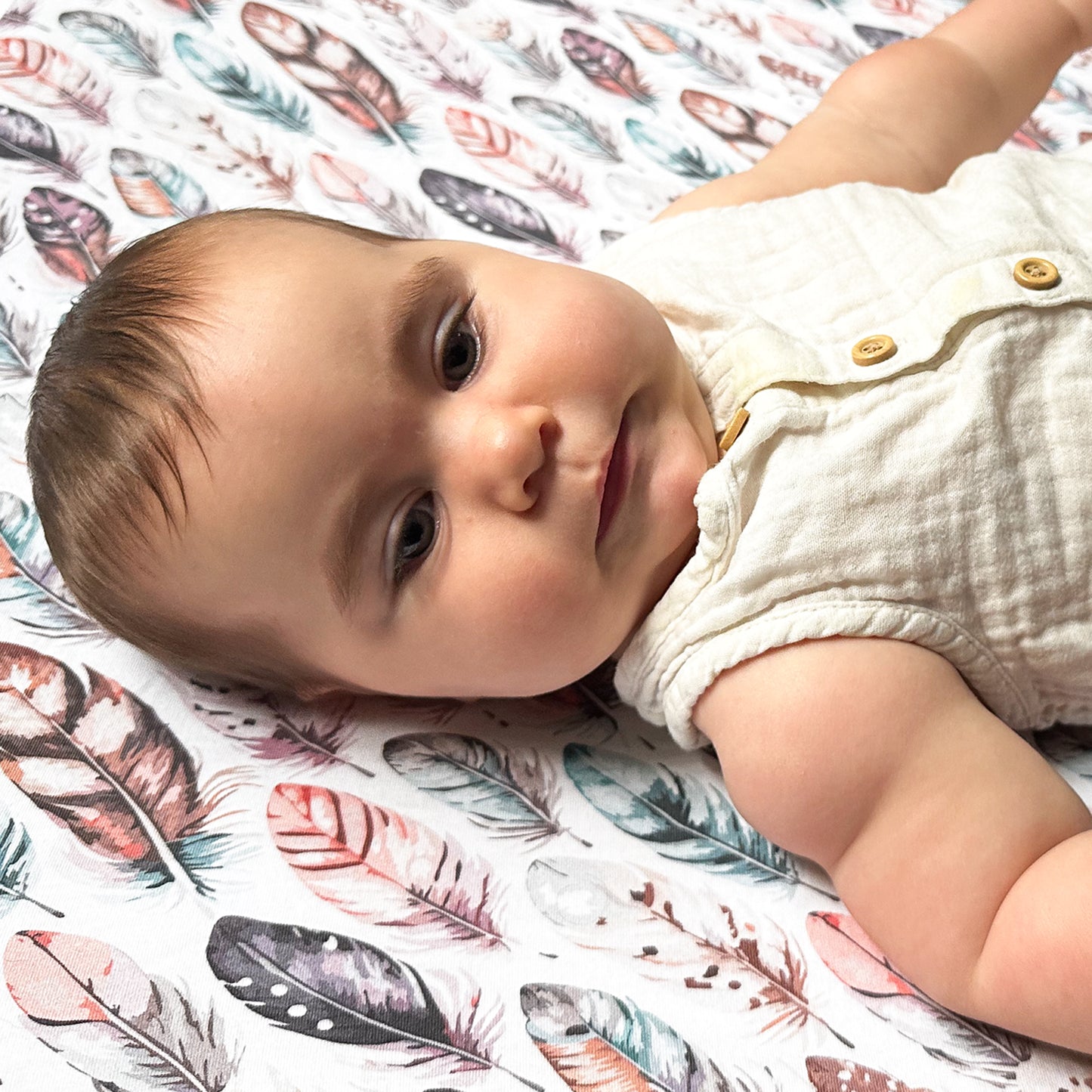 Baby lying on floral-patterned bassinet sheet inside Guava Lotus bassinet