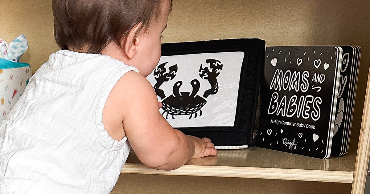 Baby exploring a shelf of high-contrast black-and-white newborn toys