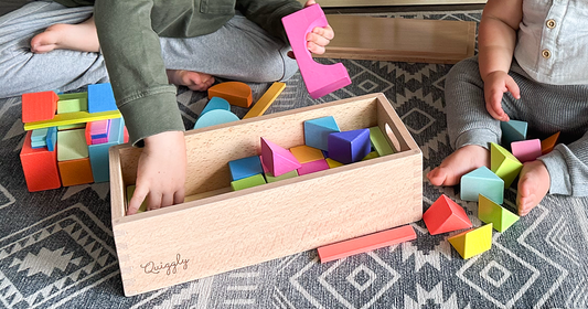 A kid & a toddler playing with Quiggly's rainbow wooden building blocks