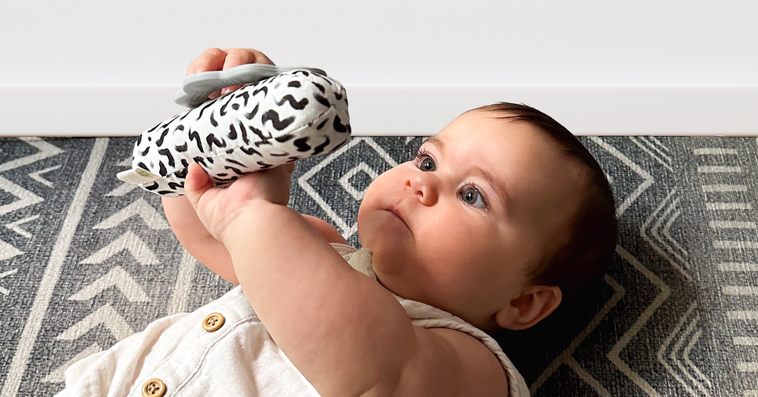 Baby focused on the hand-drawn black and white patterns of Quiggly's high-contrast newborn toy set, a unique baby shower gift