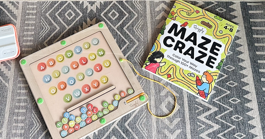Quiggly’s educational maze-themed toys - including the Magnetic Alphabet & Color Maze, and Maze Craze book - spread out across the carpet