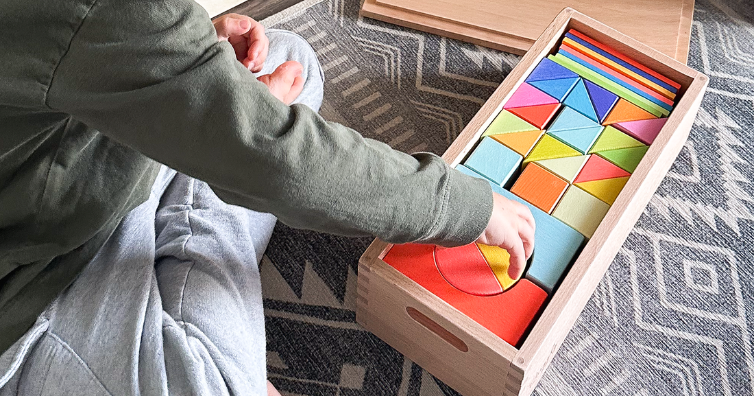 Child reaching for a wooden rainbow block from an organized Montessori-style storage box from Quiggly