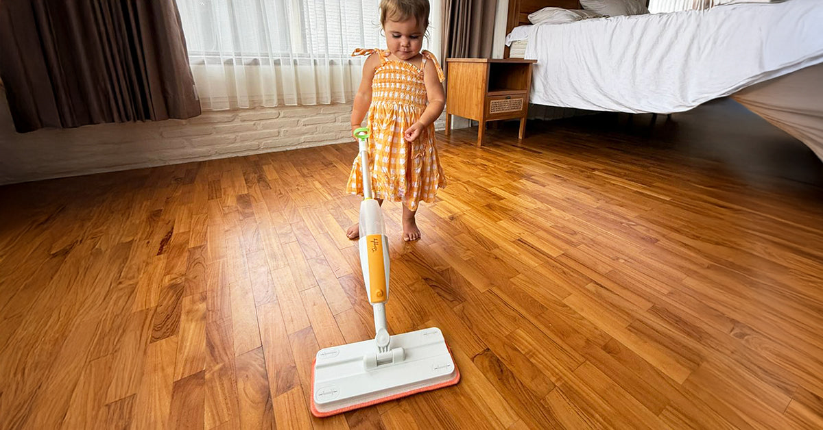 Toddler spraying and mopping the floor with Quiggly real toddler spray mop