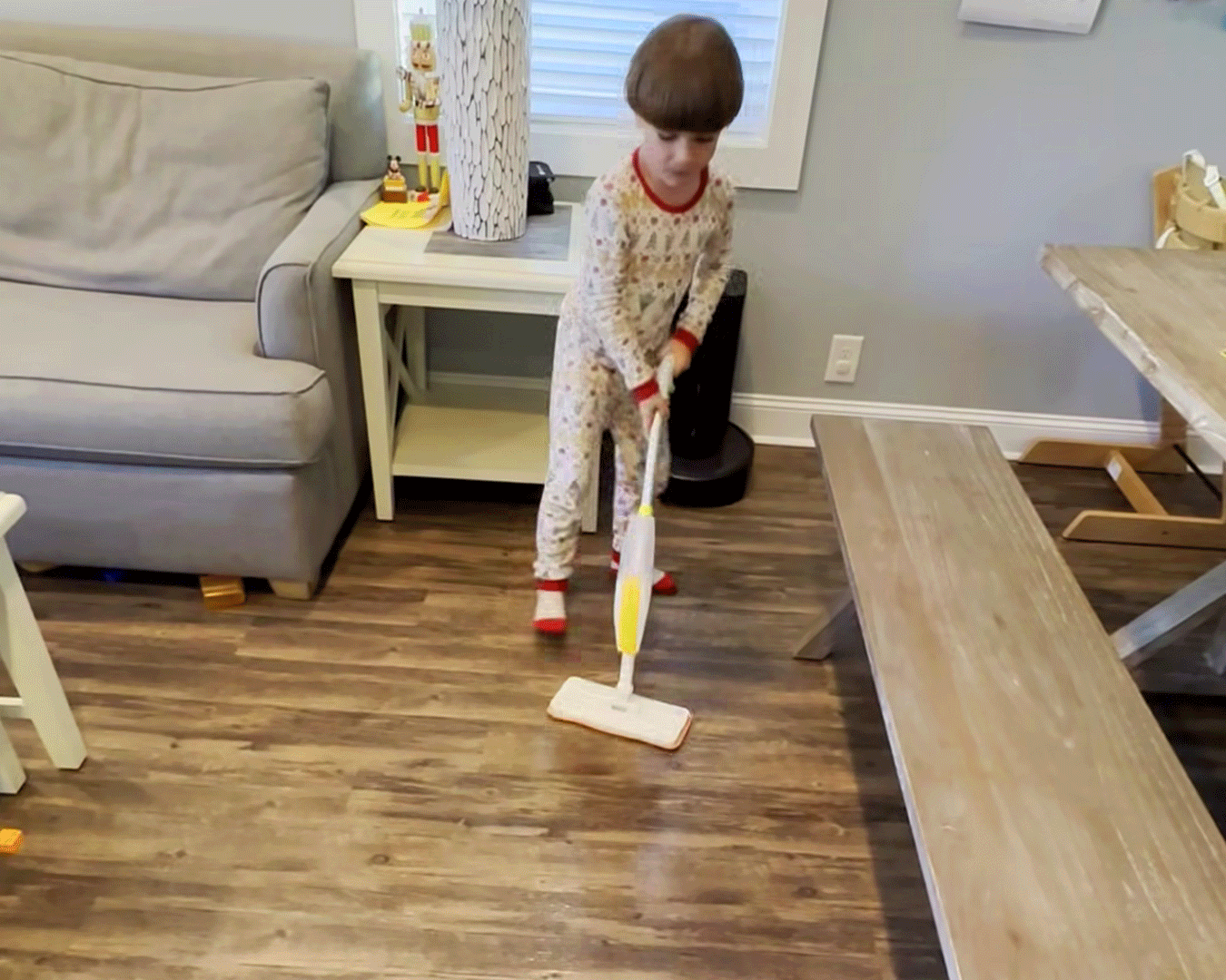 Young boy proudly mopping the floor with the Quiggly spray mop, the moment that inspired the Quiggly kids cleaning movement