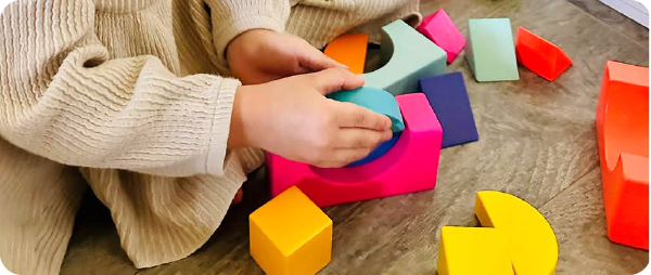 A girl making creative builds out of Rainbow Wooden Blocks Set
