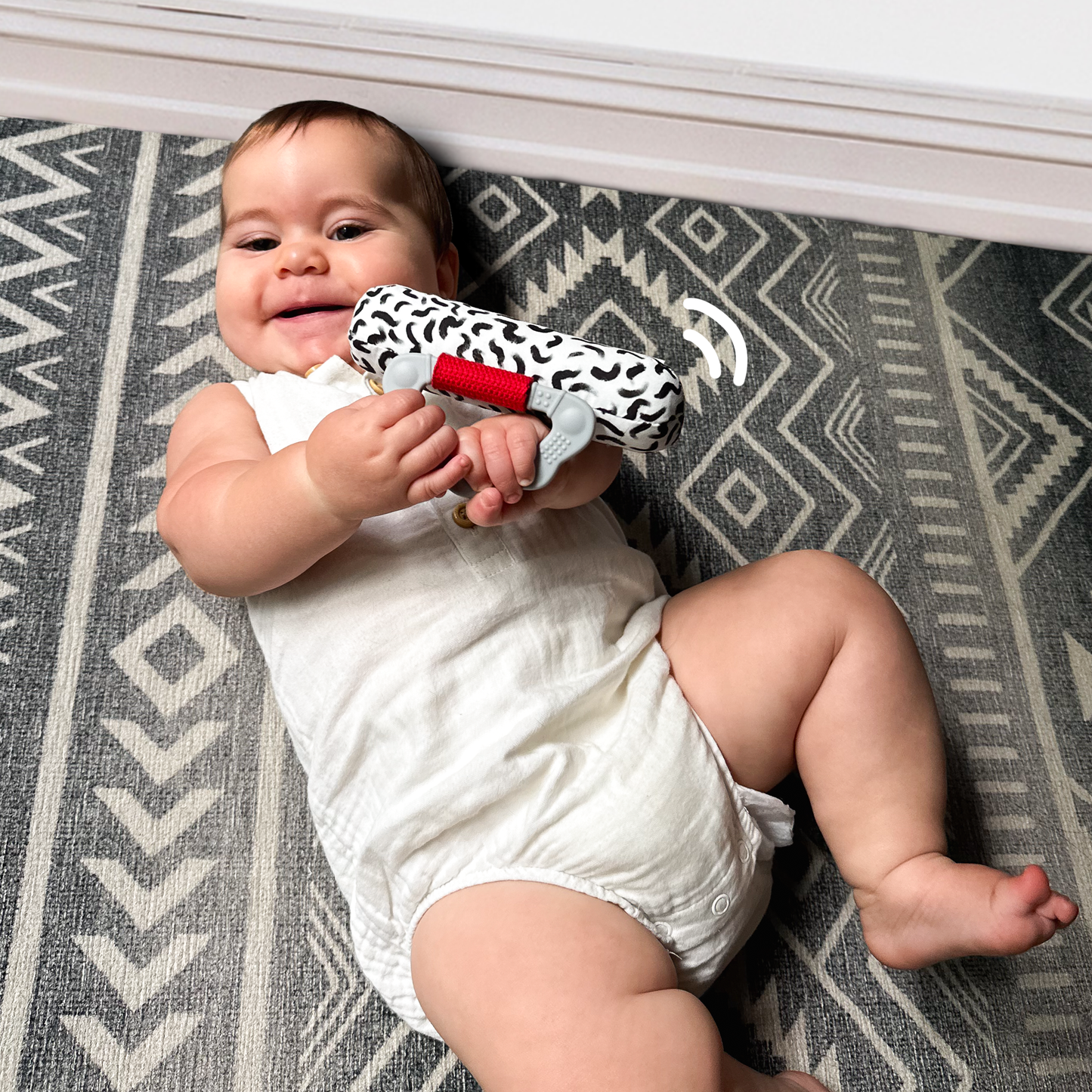 Baby playing with soft cotton rattle with silicone handle, enjoying engaging rattle sounds