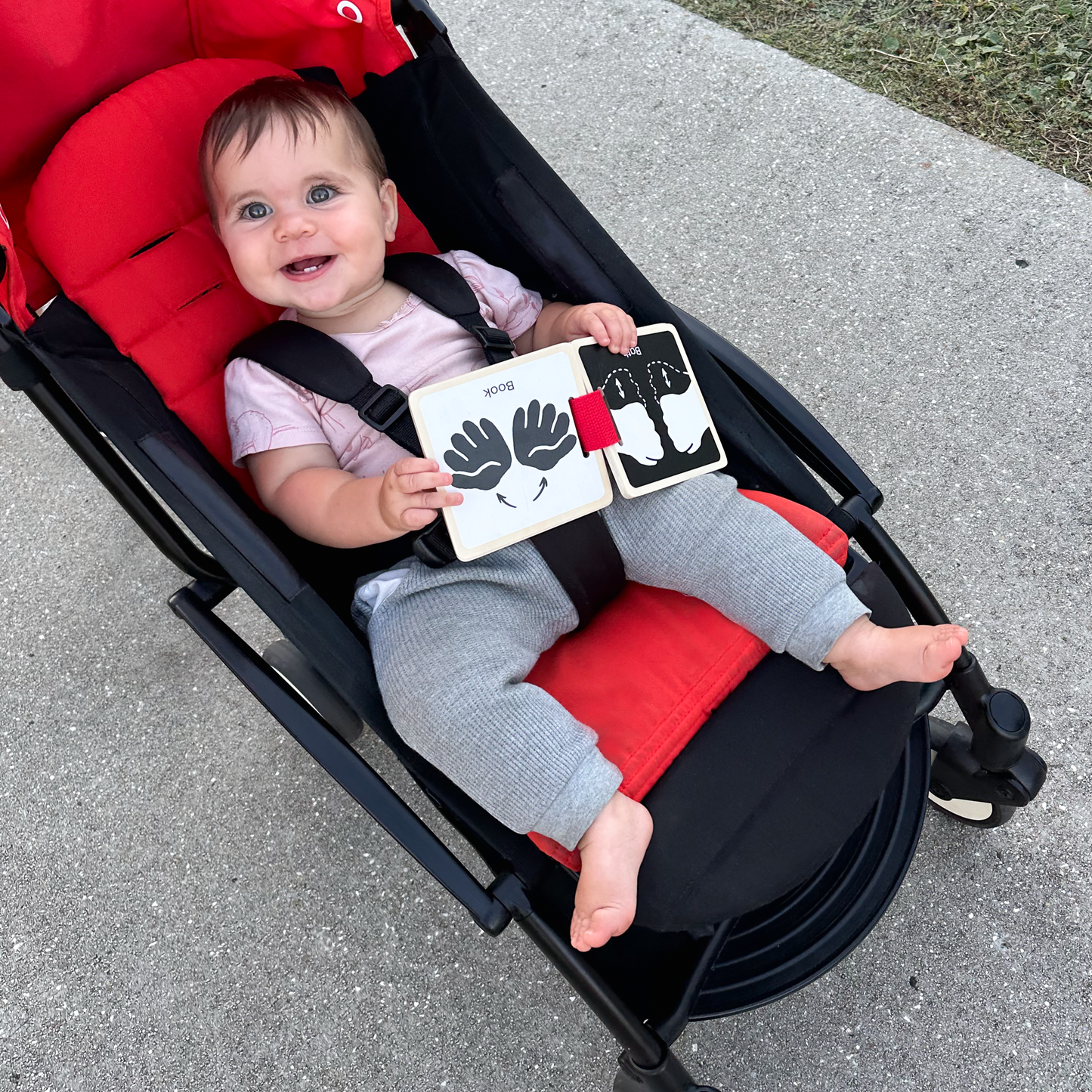 On-the-go wooden sign language book attached to stroller as baby explores outdoors