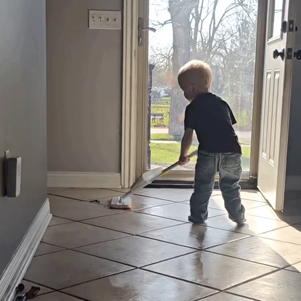 Child practicing real life cleaning skills with Quiggly kids spray mop