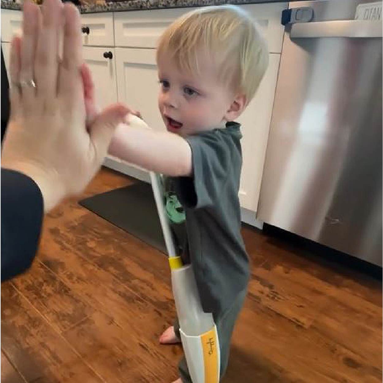 Toddler high-fiving parent after mopping the floor with Quiggly functional spray mop