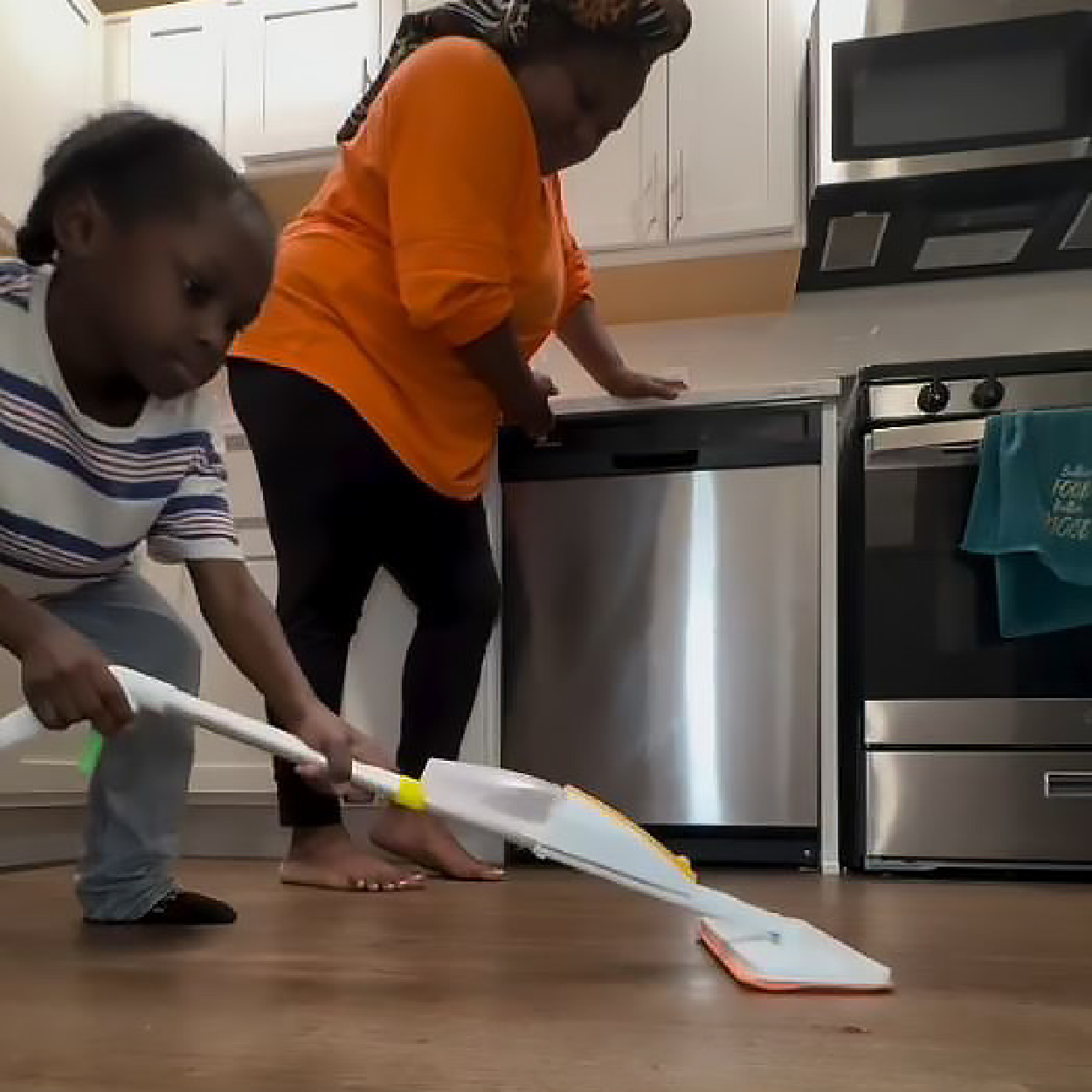 Young boy helping mom with household chores using Quiggly real kids spray mop