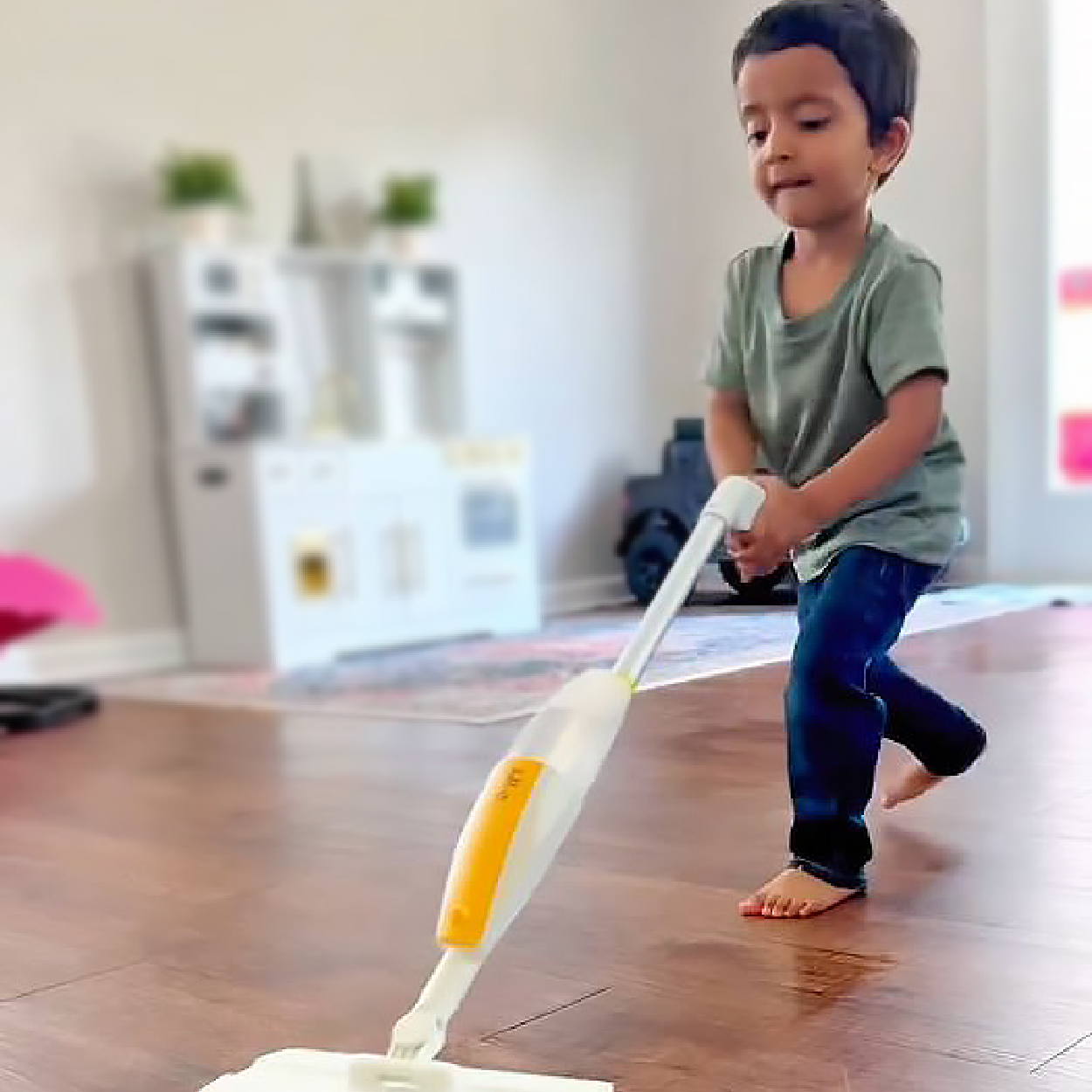 Young boy proudly mopping the floor with Quiggly real kids spray mop