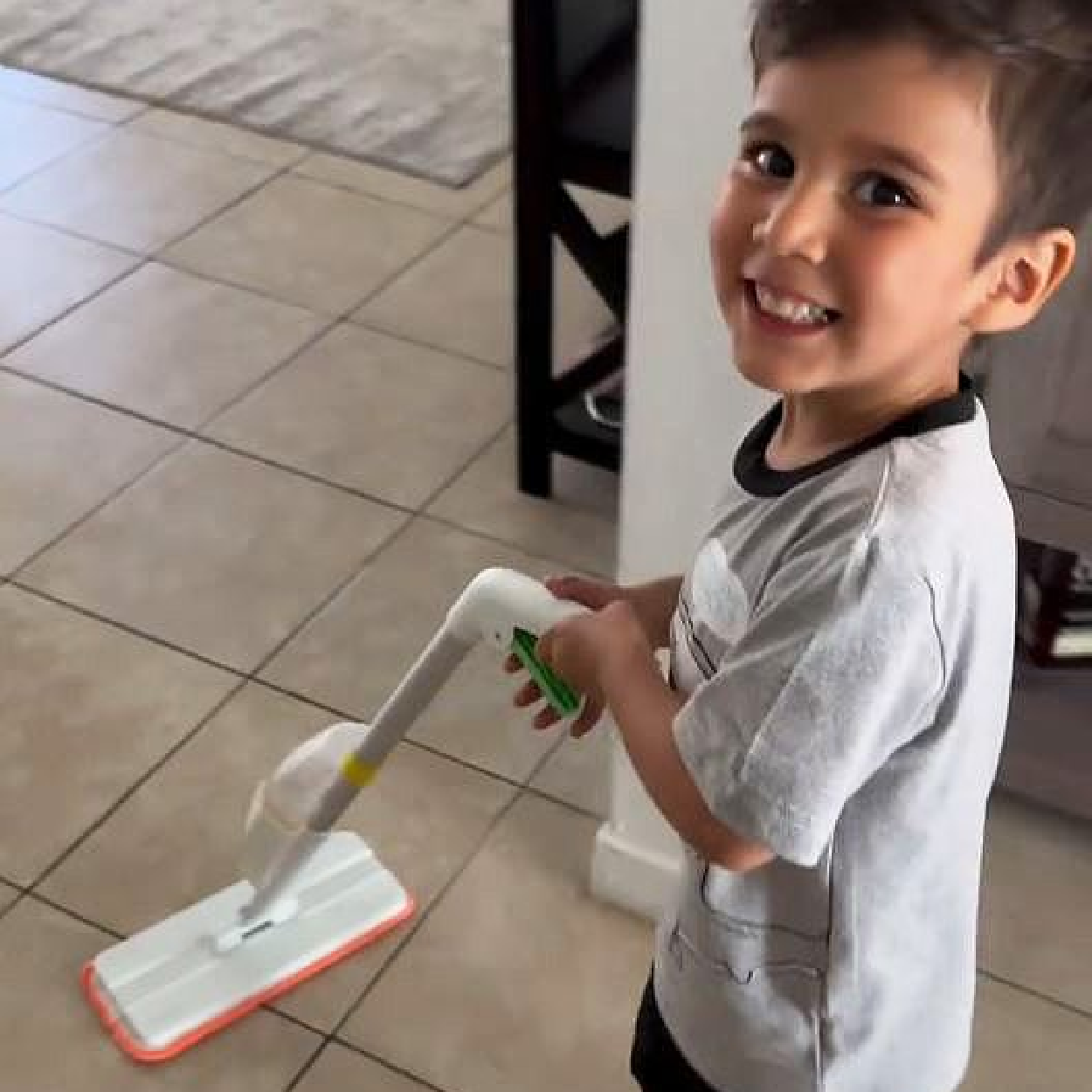 Kid learning to clean independently with Quiggly real spray mop