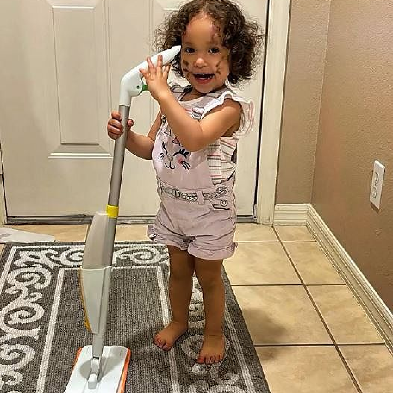 Toddler building real life cleaning habits with Quiggly spray mop