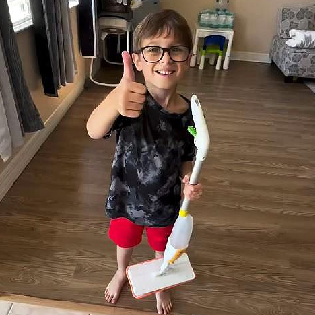 Kid giving a thumbs up while holding Quiggly real kids spray mop