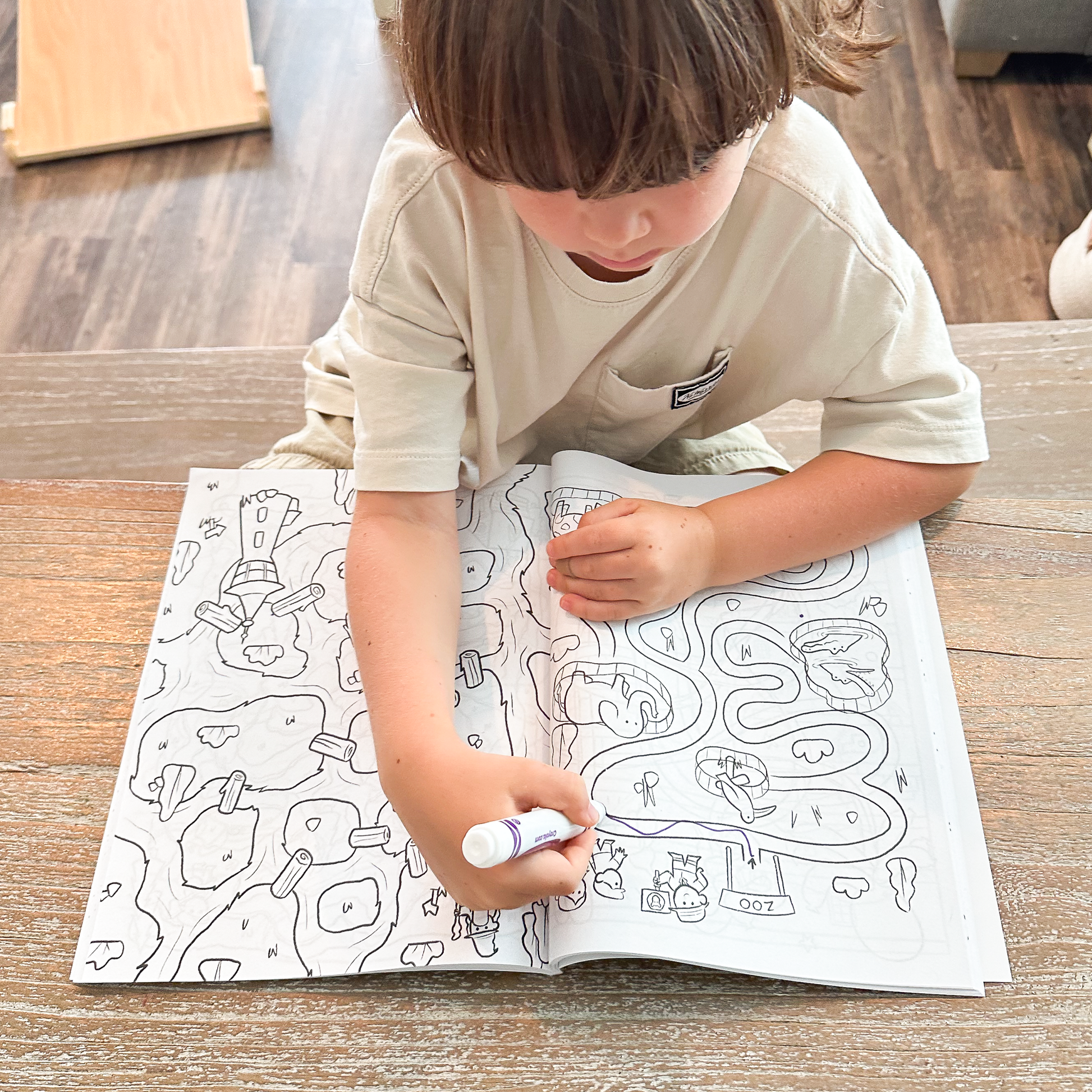 Kid holding a marker while working through a maze puzzle in Quiggly Maze Craze activity book