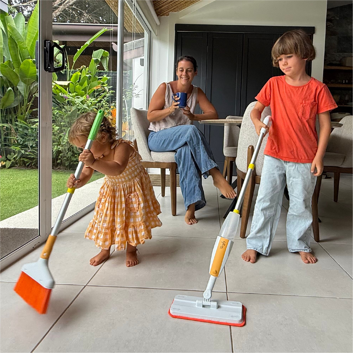 Quiggly founder proudly watching her 3 year old and 7 year old children using real kids broom and spray mop