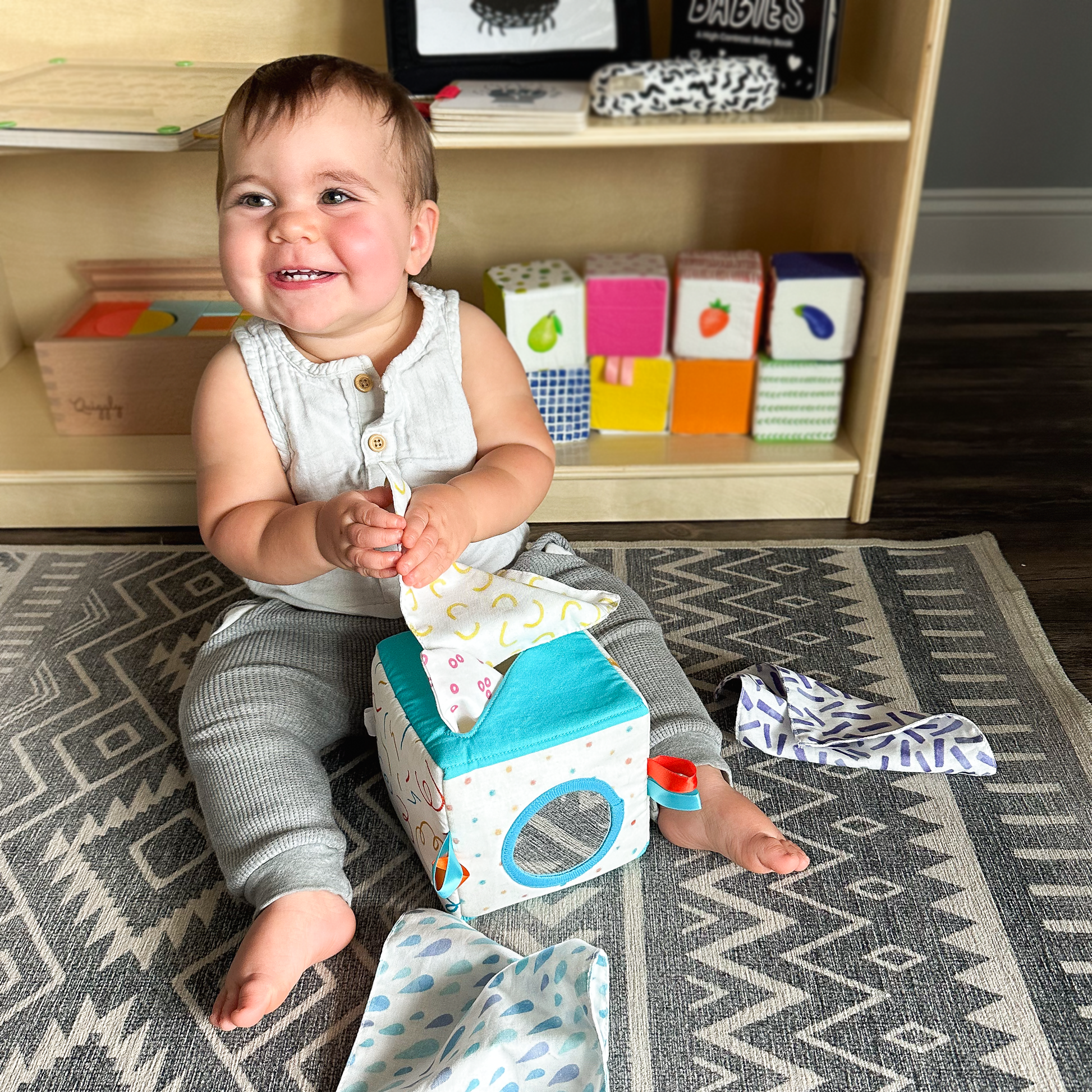 Baby giggling while playing with soft cotton tissue cloths from fabric tissue box toy
