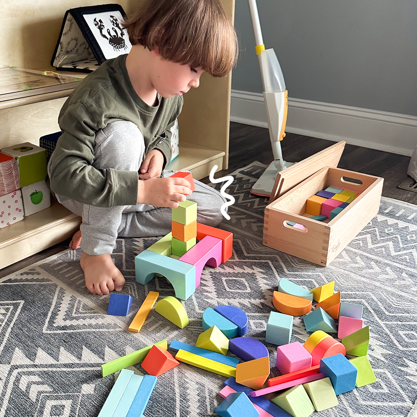 Focused child building creatively with rainbow wooden blocks set