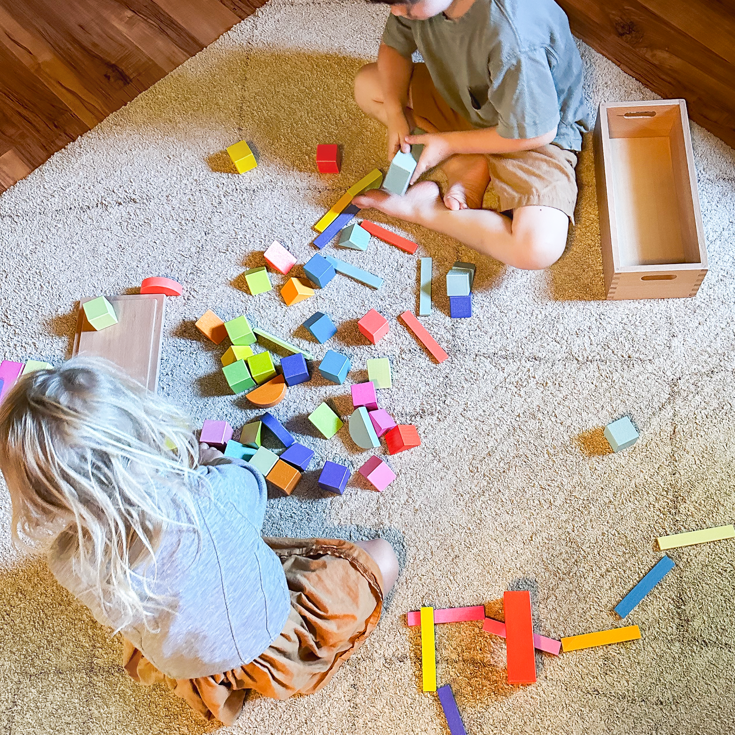 Children engaging in collaborative play with colorful wooden rainbow blocks