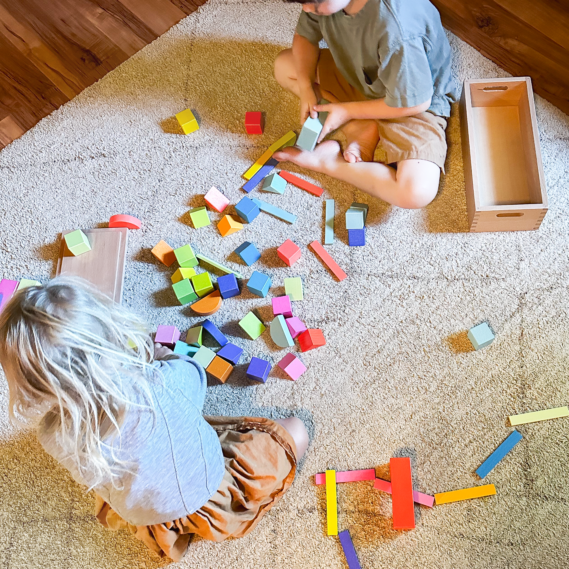 Children engaging in collaborative play with colorful wooden rainbow blocks
